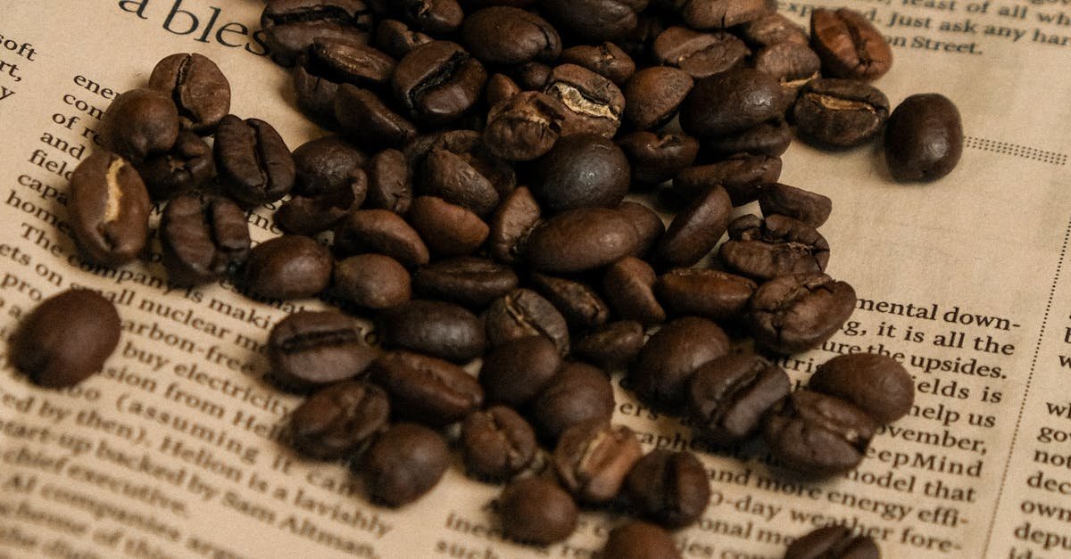 Rich coffee beans spilling from a glass on a rustic paper background.