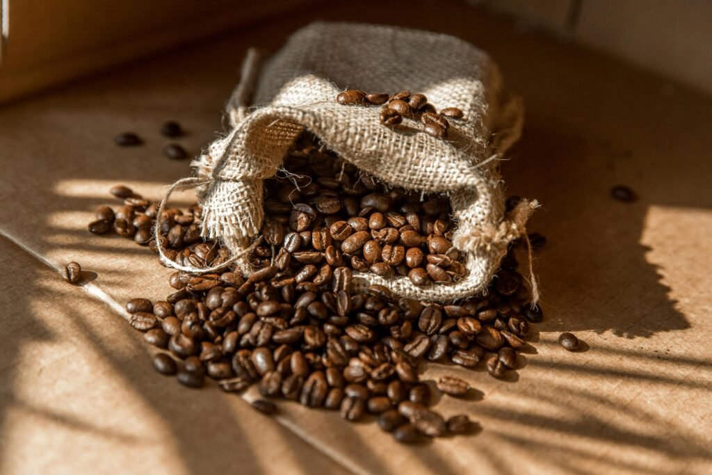 A burlap sack spills aromatic roasted coffee beans in warm natural light.